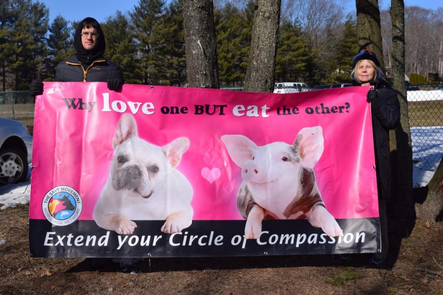 Activists David Herpst and Karen stand behind a animal equality sign