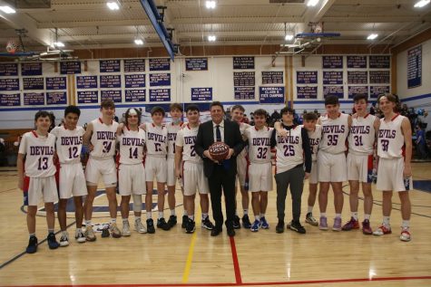 The 2021-2022 Coginchaug Basketball team presented  coach Todd Salva (center) with a game ball signed by all the players.  